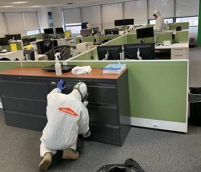 Technician wearing protective gear while cleaning a furniture in an office